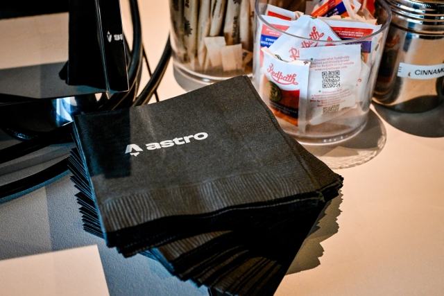 Stack of square black napkins branded with the Astro logo in white.