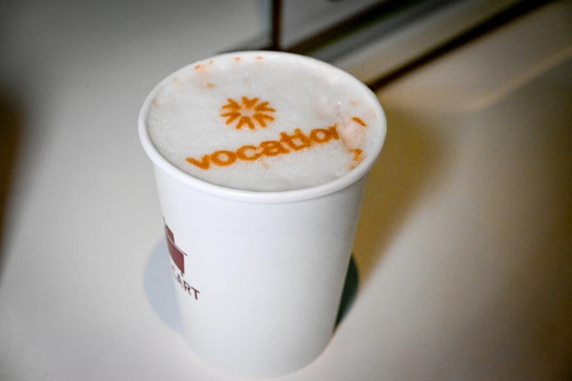 A coffee printed with the Vocation Events logo.