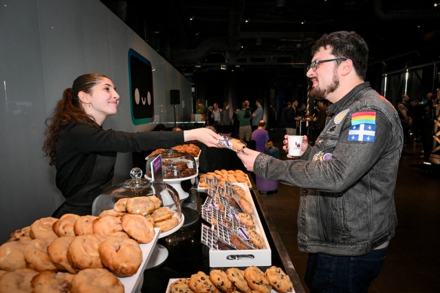 A guest being handed a gourmet cookie at the cookie bar.