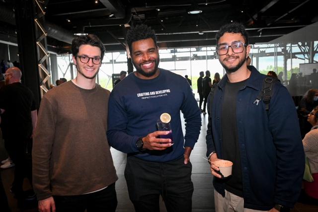 Guests posing together and smiling at the camera while holding drinks.