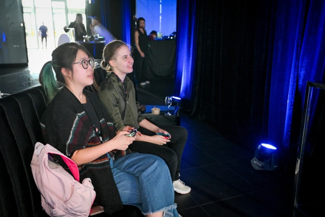 Two women looking at a TV, playing video games intently.