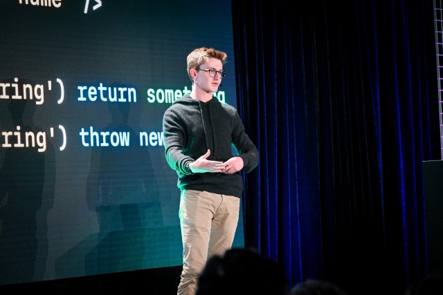 Ben Holmes on stage in front of a slide with a slide depicting form data.