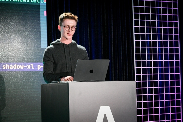 Ben Holmes speaking from an Astro-branded podium. He is typing on a laptop.