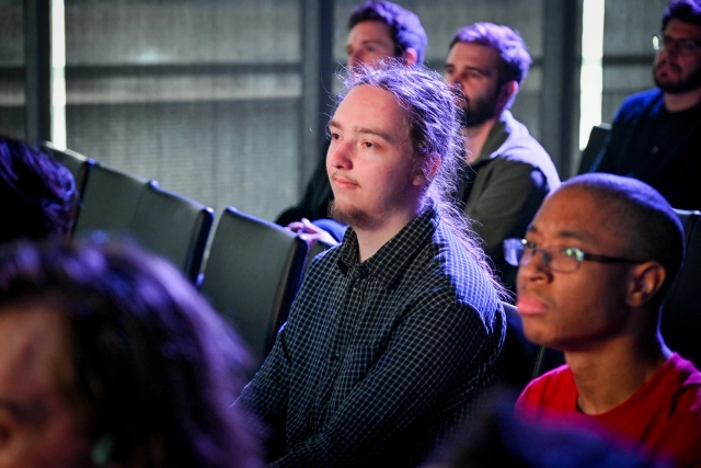 Audience members listening to Sarah Rainsberger speaking on stage.