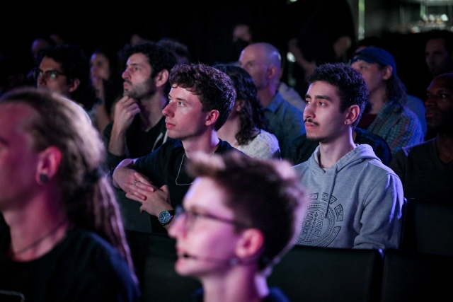 Audience members listening to Fred K. Schott speak on stage.