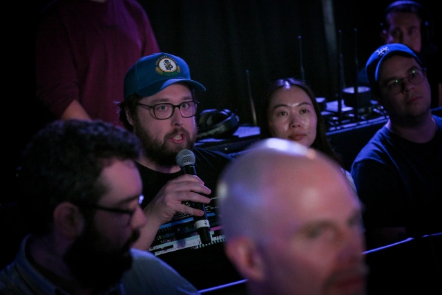 An audience member holding a microphone, asking keynote speakers a question.