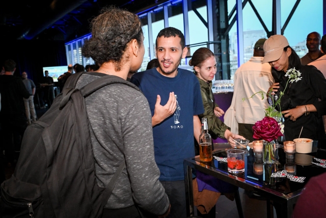 Guests mingle and chat at high tables with their drinks.