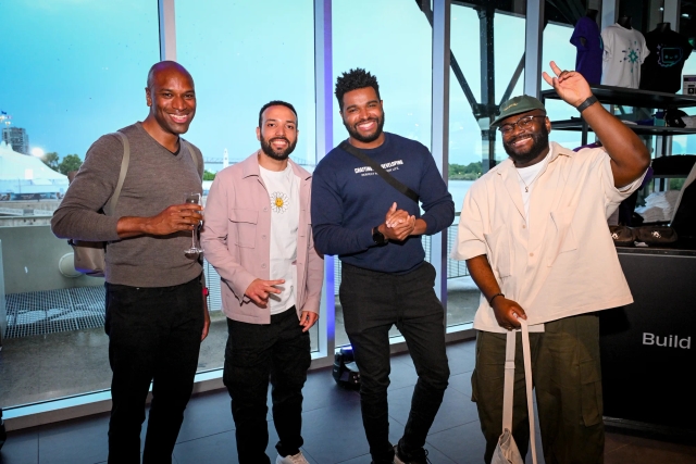 Guests pose for a group photo in front of floor-to-ceiling windows.