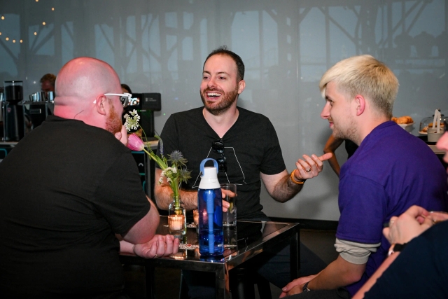 Astro team members Nate Moore, Ema Stoppa, and Alex chat with each other at a high table.