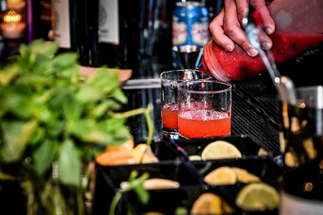 Closeup of a bartender pouring a pink drink.