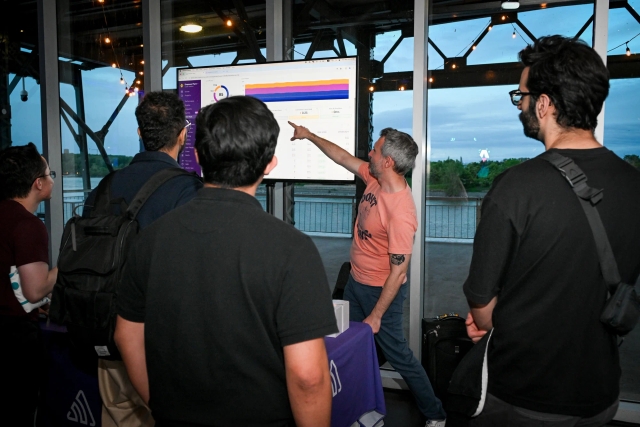 Sentry rep pointing to a chart on the TV screen at their sponsor booth.