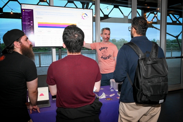 Guests watch intently as Sentry shares a demo on the TV at their sponsor booth.