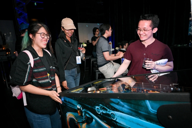 Guests laughing as they play pinball.