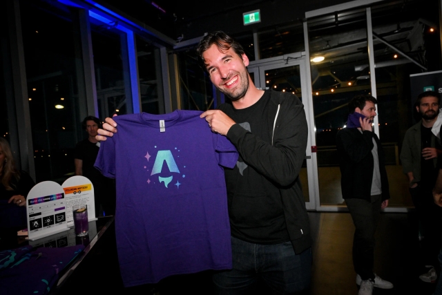 Fred K. Schott posing with a purple Astro logo printed t-shirt.